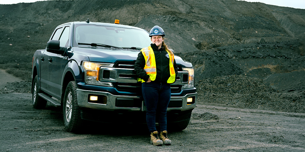 Woman in front of a truck in front of a mineral mining area