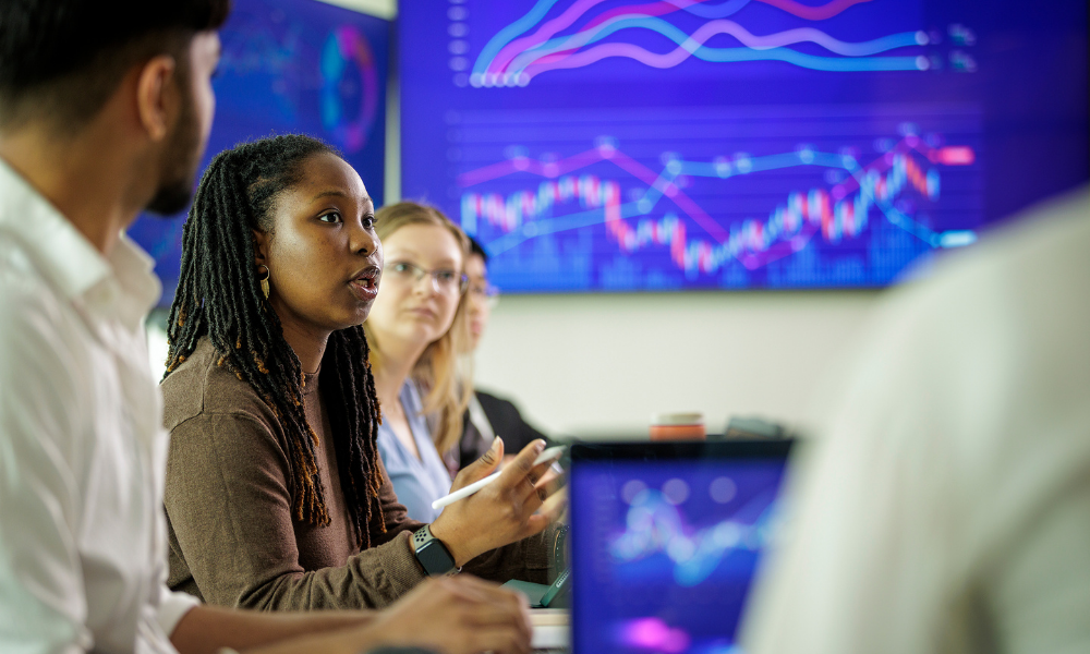 Students in a class discuss while data is shown on screens in the classroom