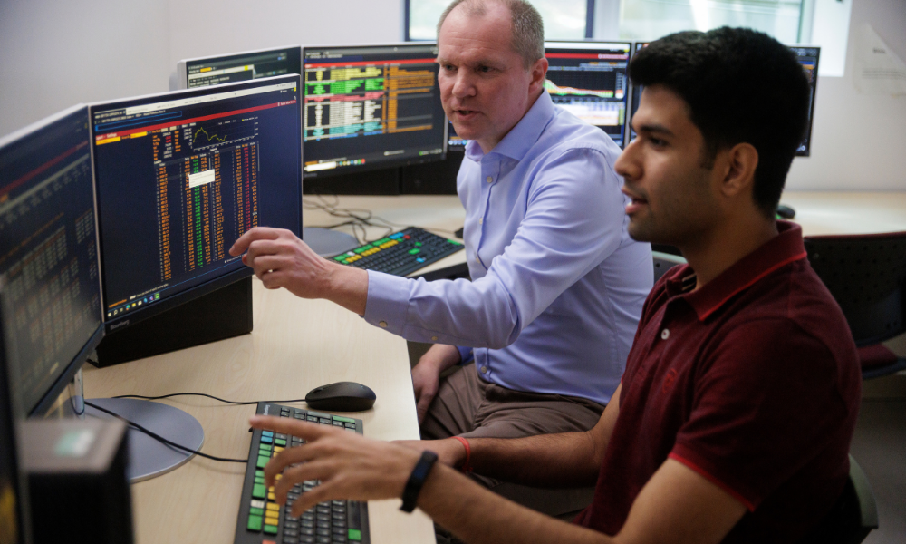 A student and Professor Meunkel look at finance data on a computer screen