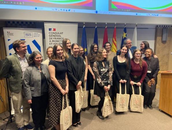 A group of smiling students holding tote bags