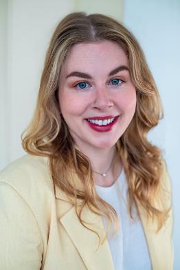 An image of a woman in a yellow blazer looking at the camera and smiling.