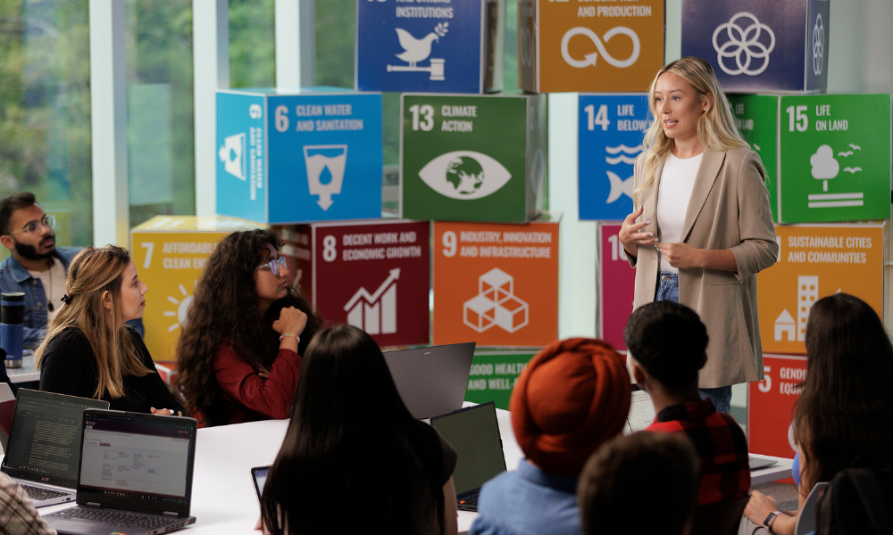 A student presents in front of colourful  Sustainability Goal blocks