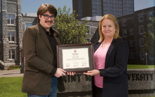 Spencer accepts a leadership award from the Dean of Arts