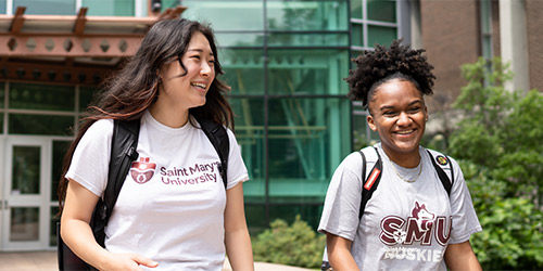 Two people walking on campus wearing Saint Mary t-shirts.