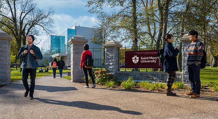 Walking students pass the Saint Mary's sign. Other students stand nearby.