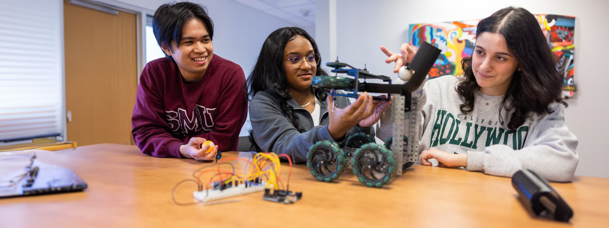 Three Engineering students work on a small robot.