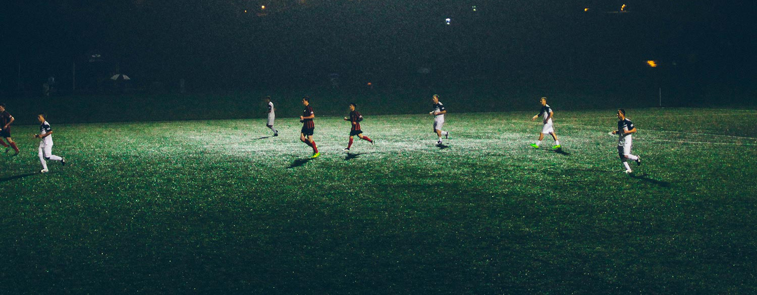 Men playing soccer under lights.