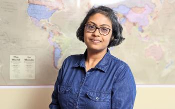 Madhuparna Gupta standing with a backdrop of a world map